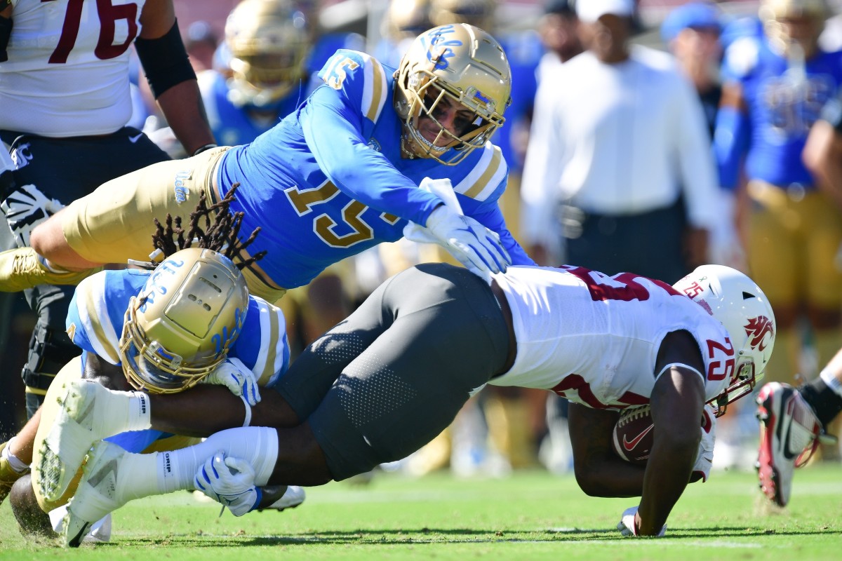 Washington State Cougars running back Nakia Watson (25) is brought down by UCLA Bruins defensive lineman Carl Jones Jr. (4) and defensive lineman Laiatu Latu (15). Mandatory Credit: Gary A. Vasquez-USA TODAY Sports